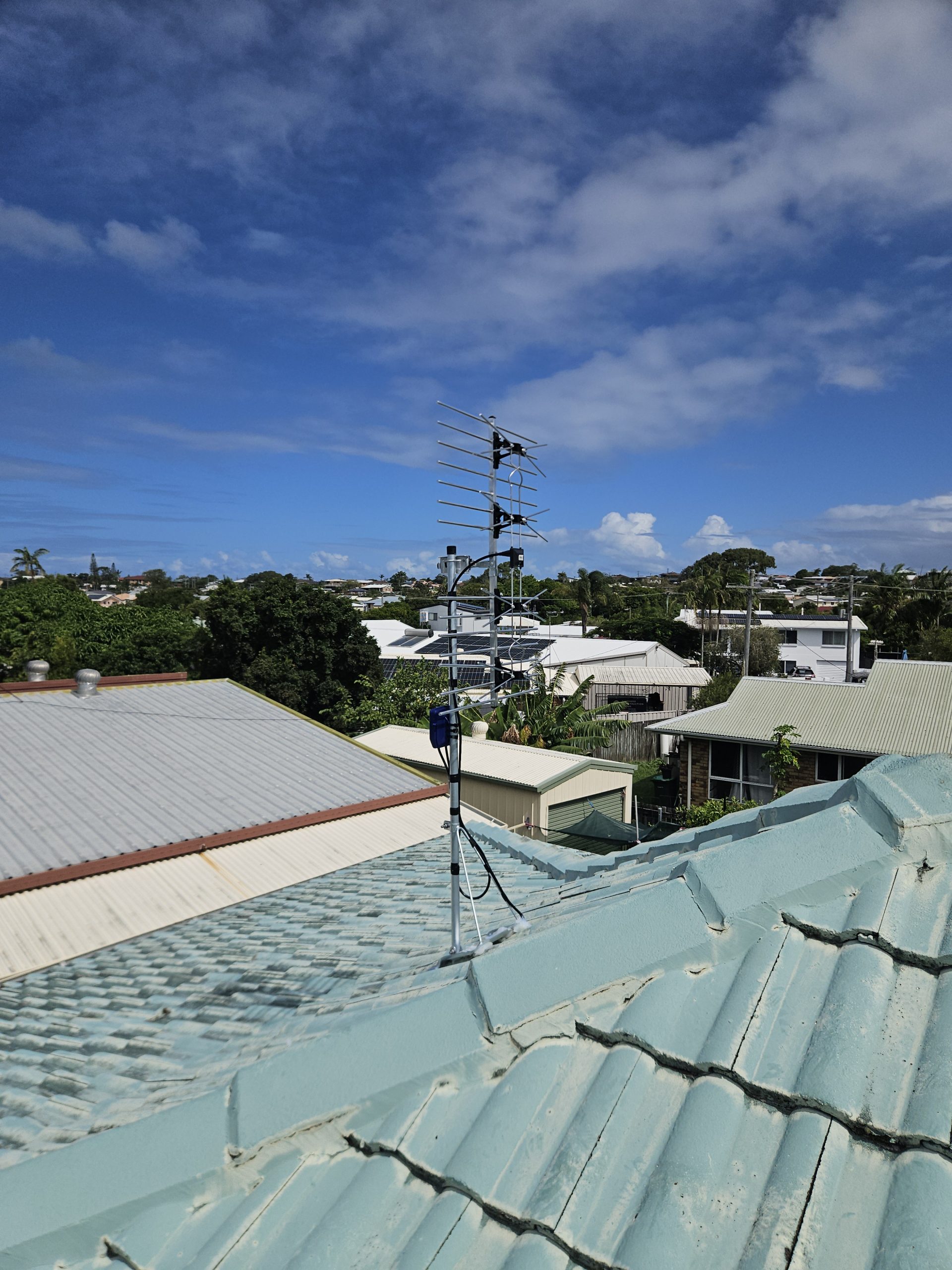 Rooftop digital TV antenna installation on Sunshine Coast with cloudy sky and surrounding homes.